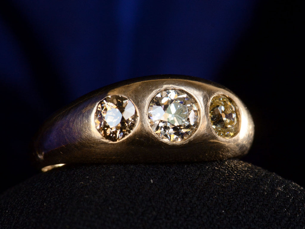 Right angled front view of c1890 Victorian Gypsy Ring with a white diamond center and a light yellow and brown diamond on either side in rosy 10k mounting.