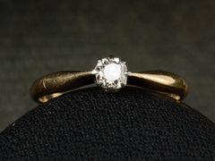 thumbnail of Front view of an antique ring with a 0.20ct old mine cut diamond set in a simple silver topped 14K yellow gold mounting, shown on dark background.