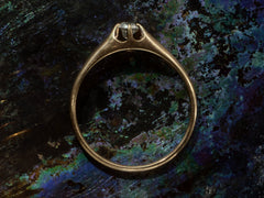 thumbnail of Side profile of an antique rosy-yellow gold Victorian engagement ring with a small old mine cut diamond in a belcher setting. Shown on dark iridescent background