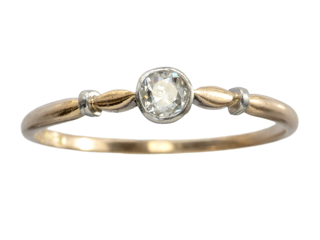 An antique Art Deco era yellow and white gold engagement ring with a bezel-set round 0.20ct old European cut diamond. Shown on white background.