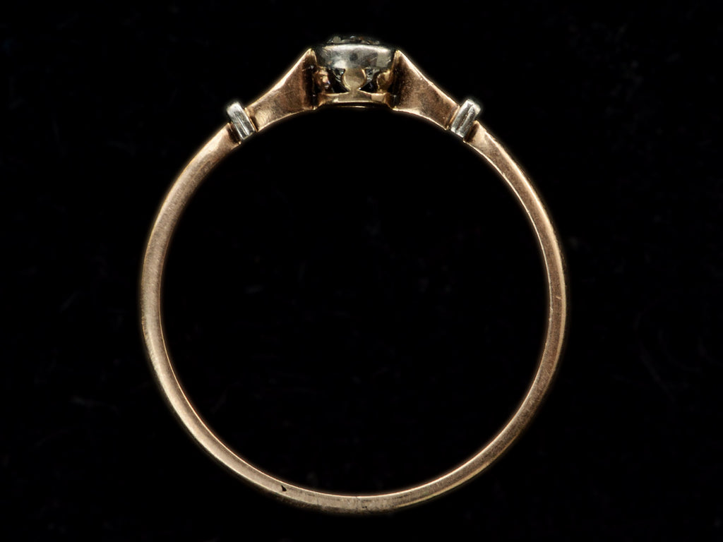 Side profile of an antique Art Deco era yellow and white gold engagement ring with a bezel-set round 0.20ct old European cut diamond. Shown on black background.