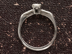 thumbnail of Side profile of a vintage c1940 white gold engagement ring with small round diamond and rectangular baguettes on either side. Shown on dark background.