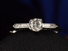 thumbnail of Front view of a vintage c1940 white gold engagement ring with small round diamond and rectangular baguettes on either side. Shown on dark background.