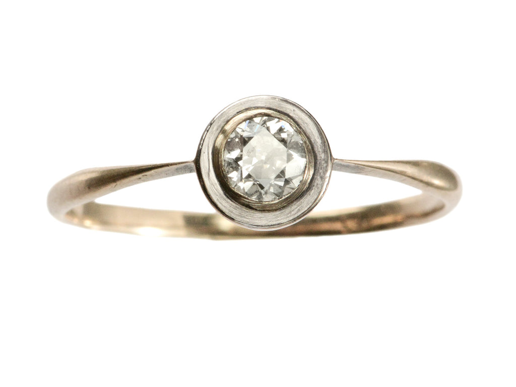 An antique Edwardian era engagement ring with a round diamond in a simple silver topped rosy-yellow gold mounting, shown on white background.