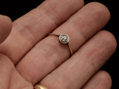 thumbnail of An antique Edwardian era engagement ring with a round diamond in a simple silver topped rosy-yellow gold mounting, shown on finger.