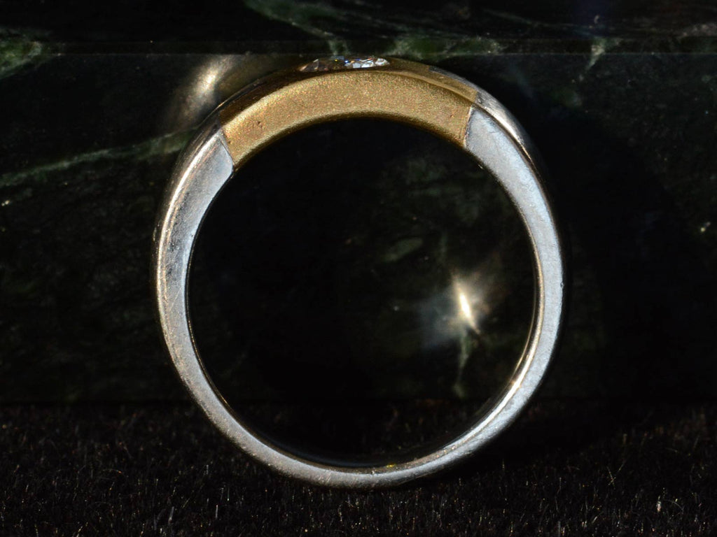 Side profile view of vintage two toned platinum and yellow gold band set with a round diamond, shown on a dark background.