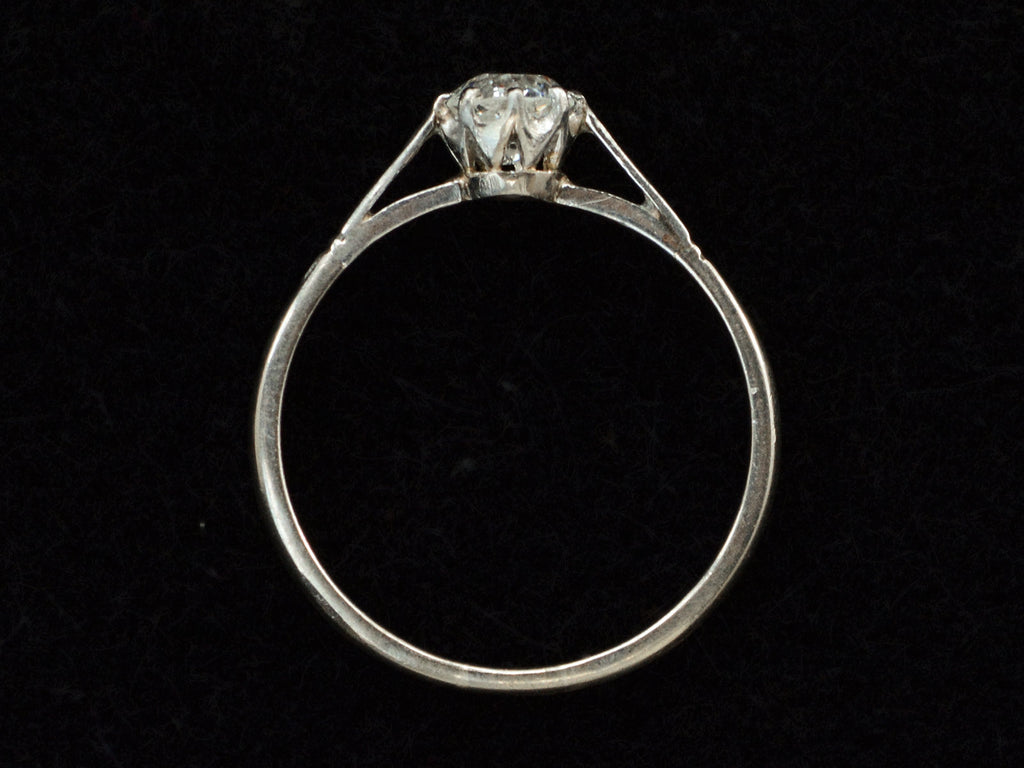 Side profile of a simple 1920 solitaire engagement ring with a old European cut diamond set in 18K white gold, shown on black background.