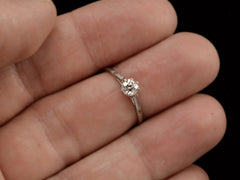 thumbnail of A simple 1920 solitaire engagement ring with a old European cut diamond set in 18K white gold, shown on finger.