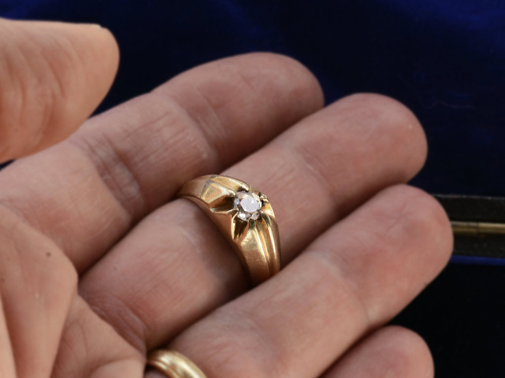 Wide antique men's ring with cushion shaped old cut white diamonds set in yellow gold, shown on finger