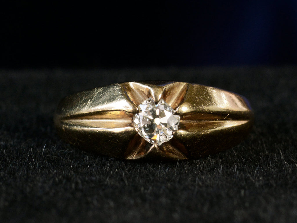 Front profile view of wide antique men's ring with cushion shaped old cut white diamonds set in yellow gold, shown on dark background.