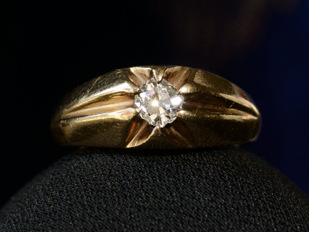 Front profile view of wide antique men's ring with cushion shaped old cut white diamonds set in yellow gold, shown on propped on black crepe ring box.