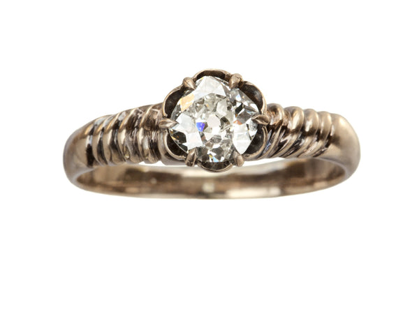 A Victorian solitaire ring with a square old mine cut diamond set in a wide striped rose gold setting, shown on white background.