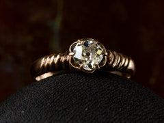 thumbnail of Detail of diamond in a Victorian solitaire ring with a square old mine cut diamond set in a wide striped rose gold setting, shown on dark background.