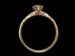 thumbnail of Side profile of Victorian solitaire with a slightly oval shaped diamond set in a pattered slender rose gold mounting, shown on dark background.