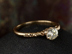 thumbnail of Elevated angled view of Victorian solitaire with a slightly oval shaped diamond set in a pattered slender rose gold mounting, shown on dark background.