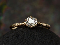 thumbnail of Front view of Victorian solitaire with a slightly oval shaped diamond set in a pattered slender rose gold mounting, shown on dark background.