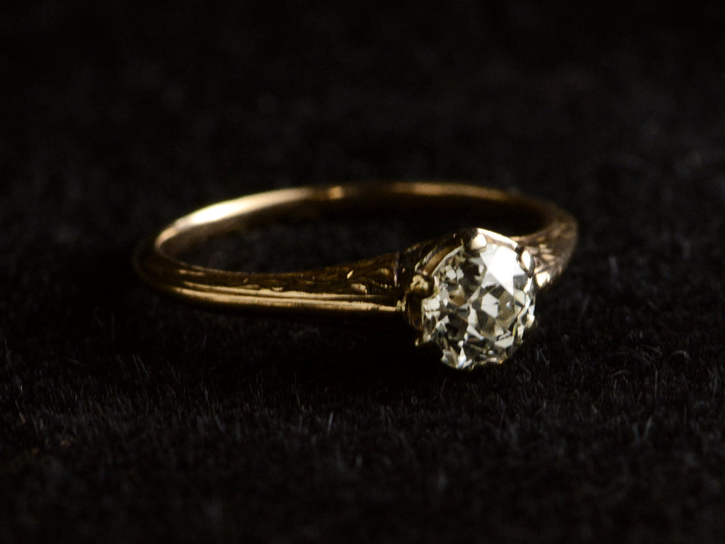 Angled view of antique engagement ring with a 0.75ct old European cut diamond set in a detailed 14K rose gold mounting, shown on dark background.