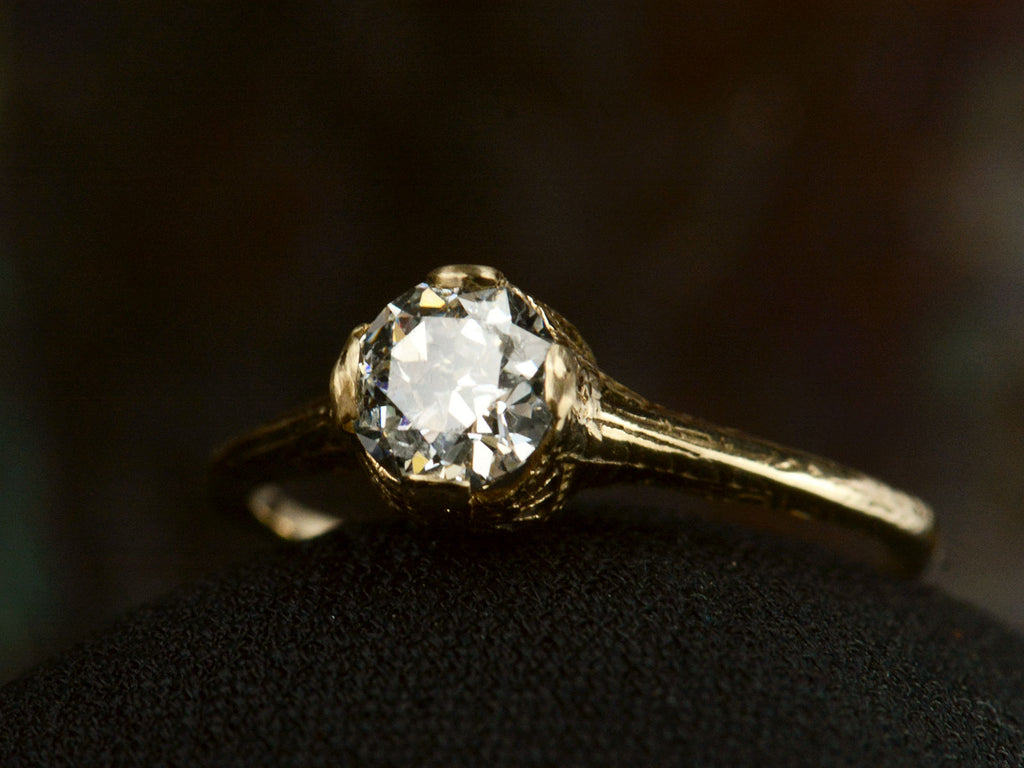 Angled front view of c1920 Art Deco yellow gold engagement ring with a 0.64ct round diamond (on dark background)