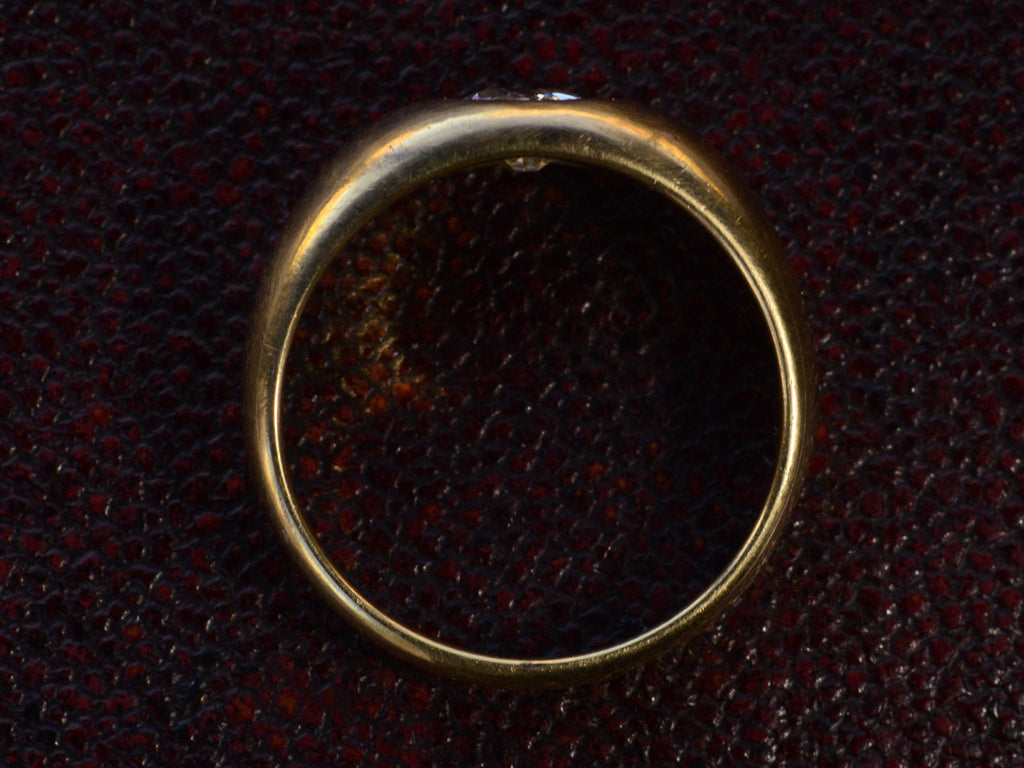Side profile of a wide rounded antique yellow gold ring with a flush-set old European cut diamond, shown on dark textured background.