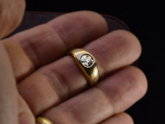 thumbnail of A wide rounded antique yellow gold ring with a flush-set old European cut diamond, shown on finger.