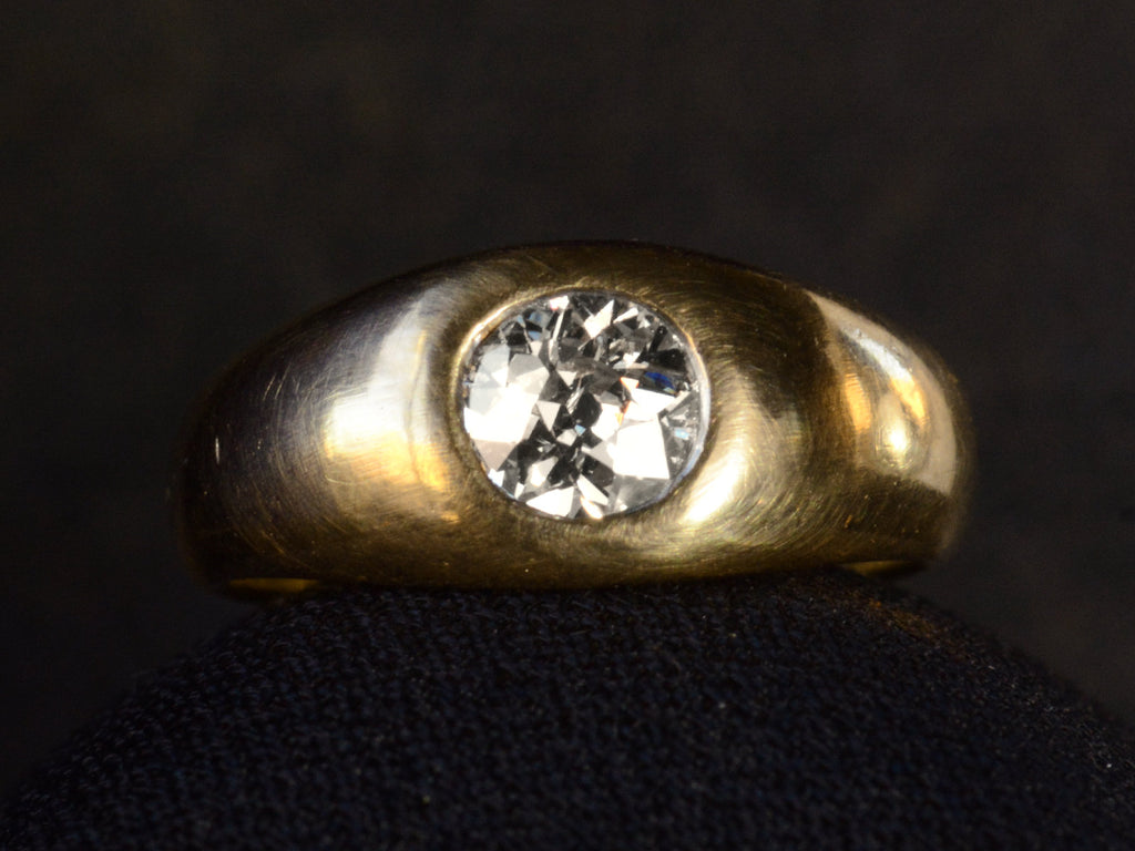 Front profile view of a wide rounded antique yellow gold ring with a flush-set old European cut diamond, shown on dark background.