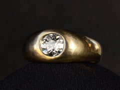 thumbnail of Right angled view of a wide rounded antique yellow gold ring with a flush-set old European cut diamond, shown on dark background.