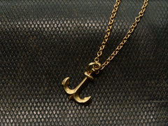 thumbnail of Gold anchor necklace on a textured black background


