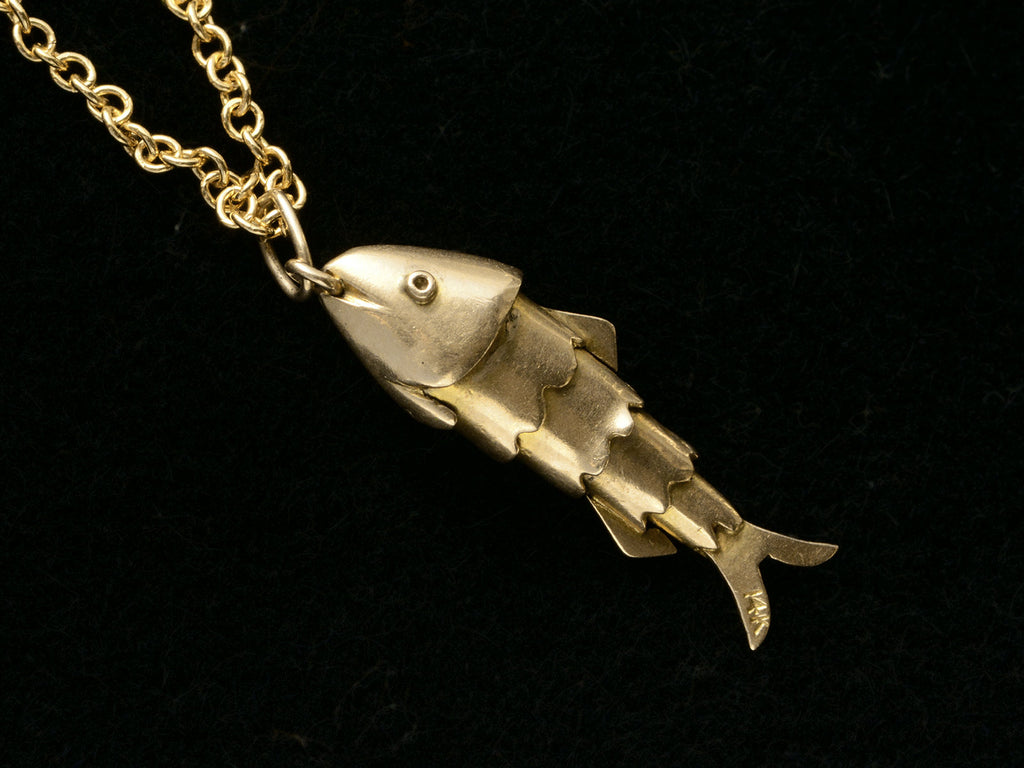 Gold fish-shaped pendant on a chain against a black background