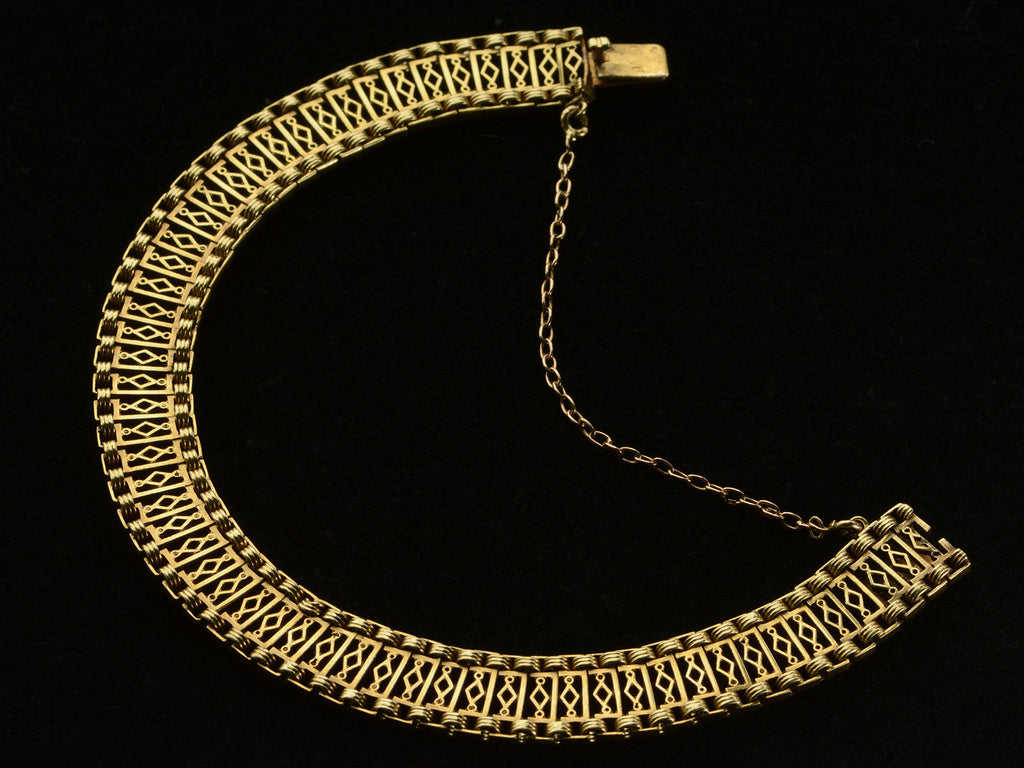 A c1880 French 18K yellow gold bracelet with filigreed links, shown opened on black background