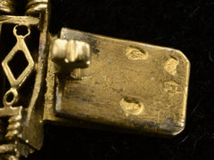 thumbnail of Close up of gold clasp tongue showing French hallmarks: two eagle head punches, an unclear animal head, and a maker's mark possibly having the letters E and C.