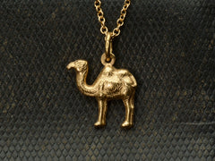 thumbnail of A c1960 18K yellow gold Camel Charm on a cable chain. A stamp on the bale reads "750" On dark textured background.