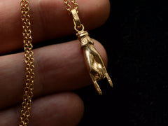 thumbnail of A vintage gold hand charm on a chain, gesturing the sign of the horns, shown held in hand.