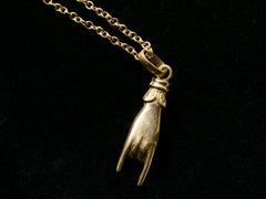thumbnail of Back of a vintage gold hand charm on a chain, gesturing the sign of the horns, shown on black background.