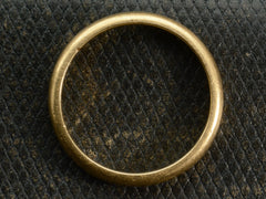thumbnail of Side profile of a rounded 18K yellow gold wedding band shown on textured dark background.