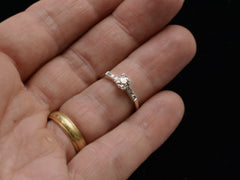 thumbnail of A simple Art Deco platinum engagement ring with a round old cut diamond in four prongs between 3 smaller diamonds on each side, shown on finger.