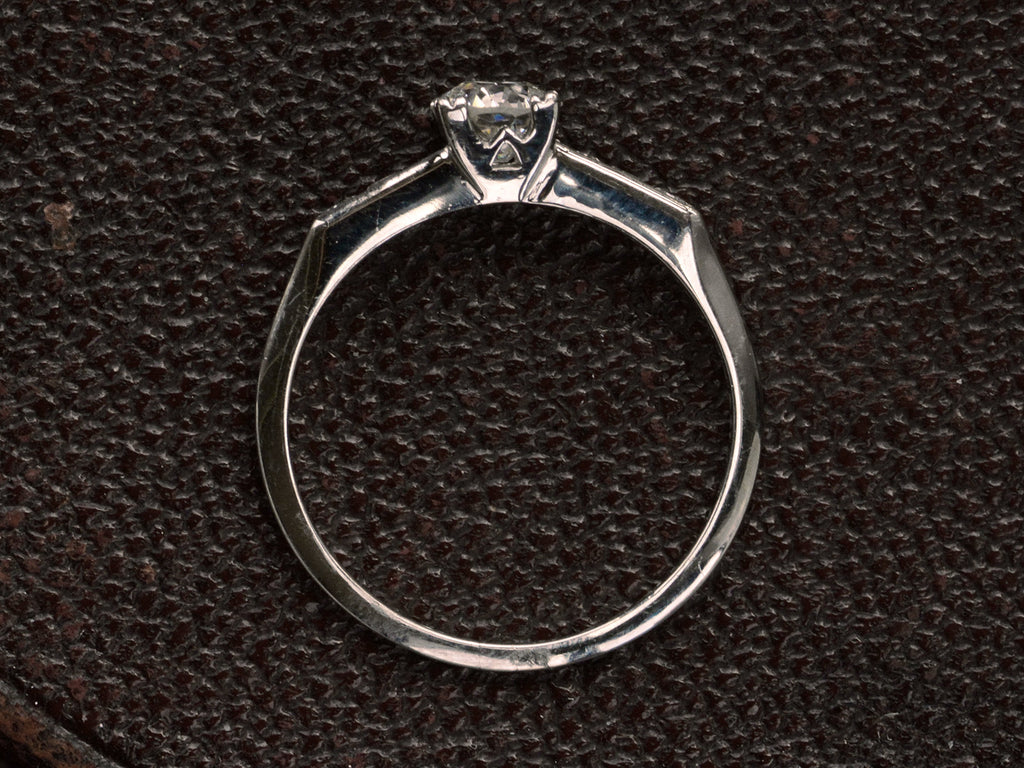 Side profile of simple Art Deco platinum engagement ring on dark textured background.