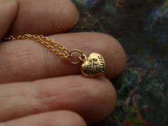 thumbnail of Gold heart-shaped pendant necklace with 'Deus Te Guie' text on a hand.
