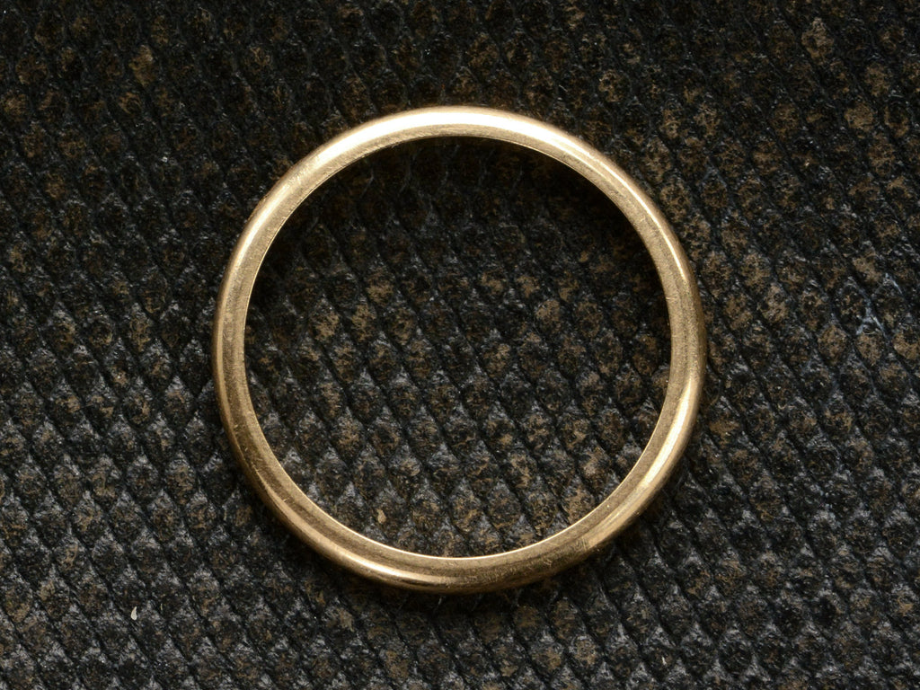 Side profile of vintage rounded 2.0mm wide gold wedding band on textured dark background.