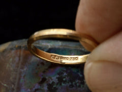 thumbnail of A narrow 18K yellow gold band with beveled edges, showing detail of stamp inside reading "74 AR SRFO 750."