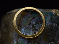 thumbnail of Side profile of a c1920 thin yellow gold Art Deco wedding band with patterning and white gold accents, shown against dark iridescent background.