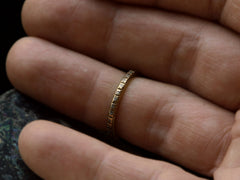 thumbnail of A c1920 thin yellow gold Art Deco wedding band with patterning and white gold accents, shown worn on finger.