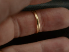 thumbnail of An antique 2.6mm wide, rounded 18K yellow gold wedding band, shown on finger