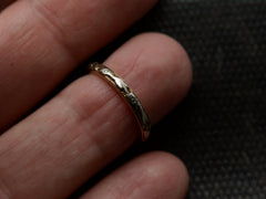 thumbnail of A yellow c1920 Art Deco wedding band with white gold decoration on the outside face, shown on finger