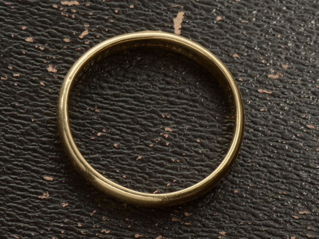 Side profile of a patinated 14k yellow gold men's wedding band with a slightly rounded profile, shown on dark background.