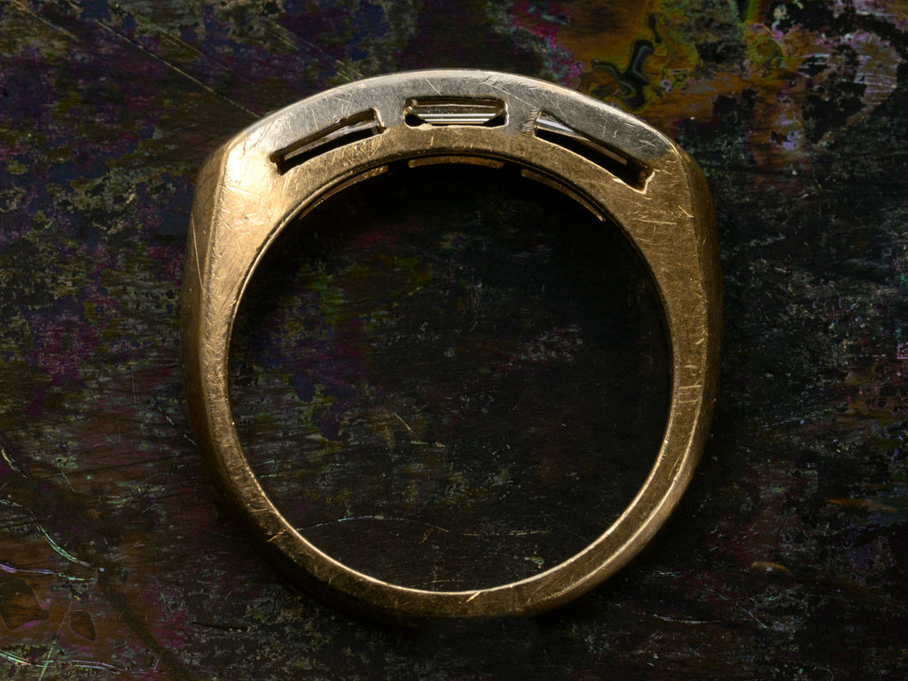 Side profile of two toned vintage ring with three diamond baguettes. Shown on dark background.