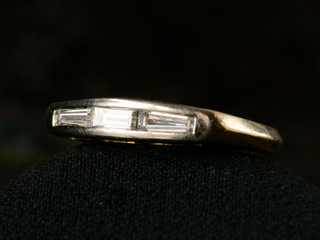 Angled front view of two toned vintage ring with three diamond baguettes. Shown on dark background.