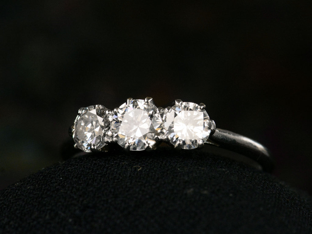 Angled front view of simple c1920 Three Diamond Ring in Platinum (on dark background)