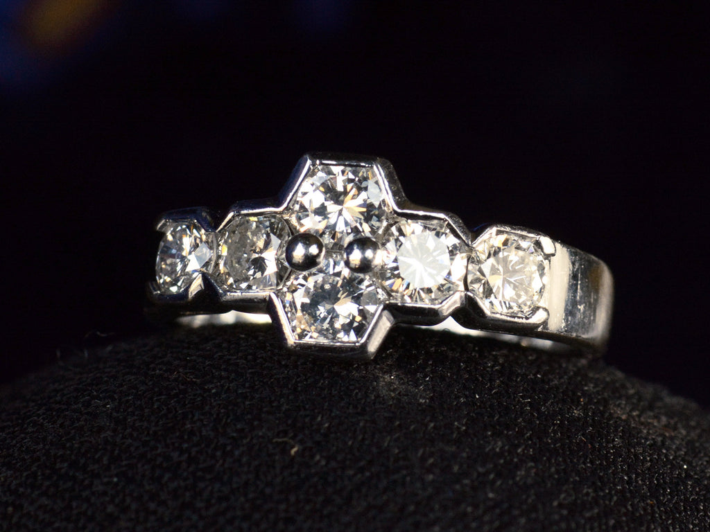 Angled view of vintage c1960 white gold ring with a cluster of six diamonds. Shown on dark background.