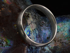 thumbnail of Angled view of wide men's platinum band with matte surface on dark colorful background.