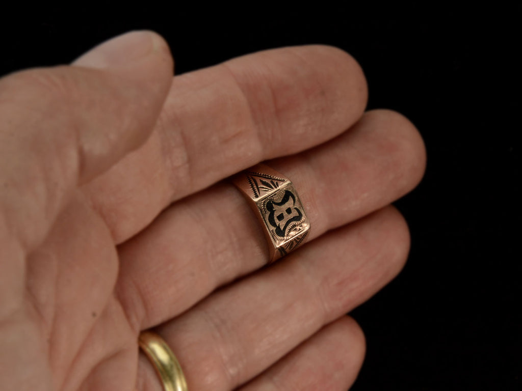 Antique c1890 Victorian signet ring in rose gold with black enamel details and the letter "B" on the face. Shown on hand for scale.